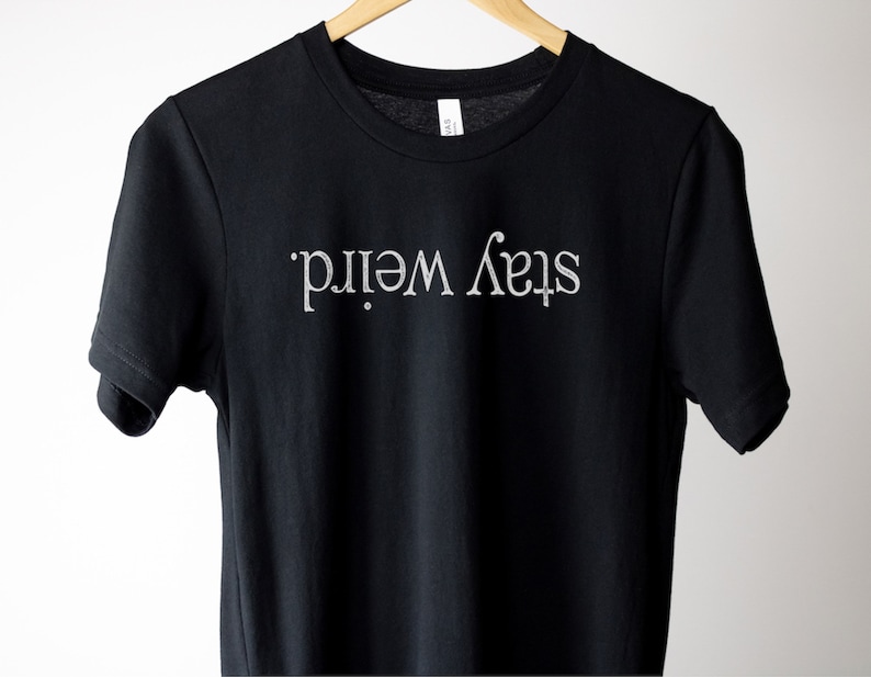 May include: Black t-shirt with the text "Stay Weird." printed in white.