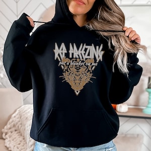 May include: Black hoodie with a gold graphic that says "I'm Freezing, put a blanket on me" and a stylized animal head.