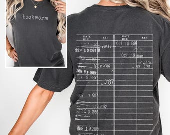 May include: A dark grey t-shirt with a white print of a library card on the back. The front of the shirt has the word "bookworm" printed in white.