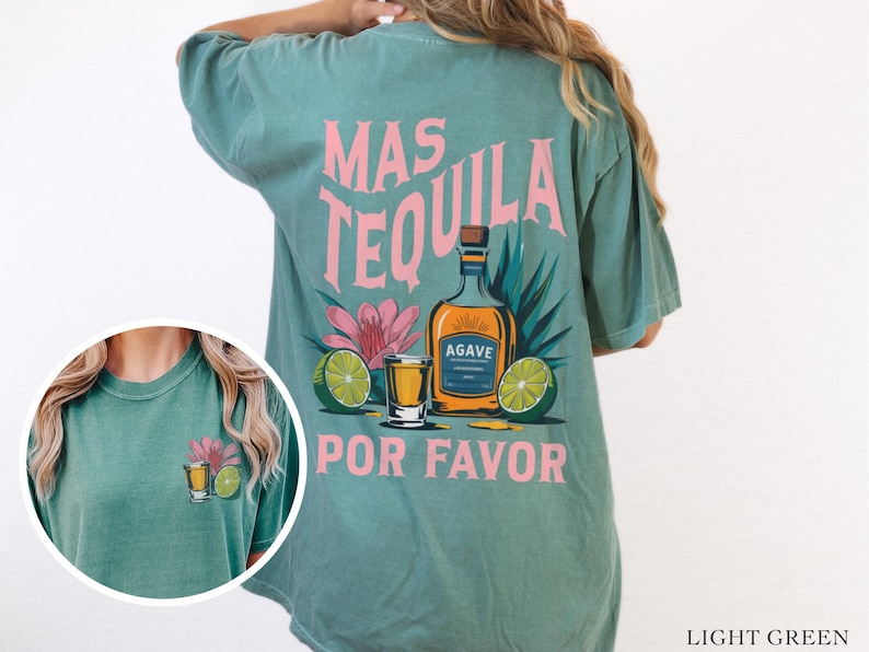 May include: Light green t-shirt with a pink graphic of a tequila bottle, limes, and a shot glass. The text on the shirt reads "Mas Tequila Por Favor".