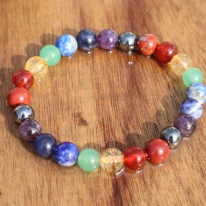 May include: A colourful beaded bracelet with seven different coloured beads representing the seven chakras. The beads are strung on a clear elastic cord.