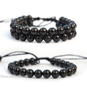 May include: Two black onyx beaded bracelets with adjustable black cords. The top bracelet has two rows of beads, while the bottom bracelet has one row of beads.