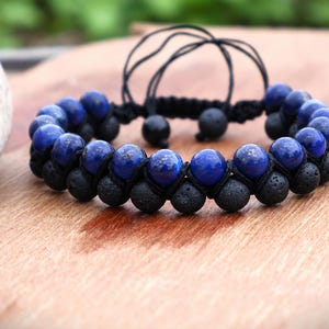 Può includere: Un bracciale a doppio filo con file alternate di perline lisce in lapislazzuli blu intenso e perline in pietra lavica nera opaca e porosa. Il bracciale è fissato con una chiusura in cordino intrecciato nero che include due piccole perline nere pendenti.