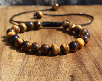 May include: A brown leather bracelet with gold and black tiger's eye beads.