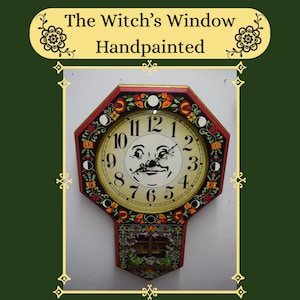 May include: An octagonal wall clock with a cream-colored face featuring a central moon face illustration and black numerals. The frame is red with floral motifs and moon phase icons. Below the clock face is a small painted window and flower box.