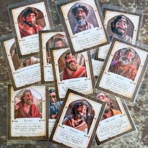 Puede incluir: Un conjunto de tarjetas ilustradas con figuras bíblicas como Daniel, Isaías y Jeremías. Cada tarjeta tiene un retrato, un nombre y una cita. Las tarjetas están en fundas protectoras, con un diseño de marco de madera.