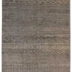 Puede incluir: Una alfombra rectangular gris con una superficie texturizada y patrones geométricos intrincados en un tono gris más claro. El diseño presenta bandas horizontales con motivos de diamantes y circulares, creando una estética sutil y elegante.