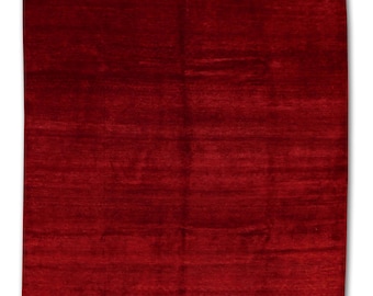 May include: A rectangular, solid red rug with a textured surface. The rug is a deep, rich shade of red, and the fibers appear to be tightly woven. The rug is likely made of wool or a similar material. The rug is suitable for a living room or bedroom.