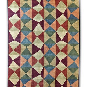 May include: Geometric patterned area rug with a black border. The rug features a repeating design of triangles and diamonds in shades of red, blue, green, and beige. The rug is rectangular.