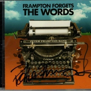 Puede incluir: Una fotografía en blanco y negro de una máquina de escribir vintage con las palabras "Peter Frampton Band" y "Phenix" en ella. La portada del álbum es para el álbum "Frampton Forgets The Words". La portada del álbum está firmada por Peter Frampton.