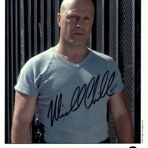 May include: A white ceramic mug with a black handle and the text "But First, Coffee" in a bold, black font. The mug is set against a blurred background, suggesting a cozy setting.