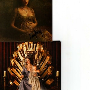 May include: A woman in a gold and green dress sits on a throne with a crown on her head. She is breastfeeding a baby. The image has a Parental Advisory label.