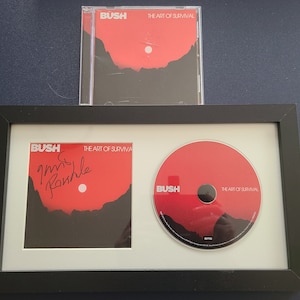 Puede incluir: Un CD y una caja de CD enmarcados del álbum "The Art of Survival" de Bush. El CD está firmado por Gavin Rossdale. La caja del CD está en una funda de plástico transparente.