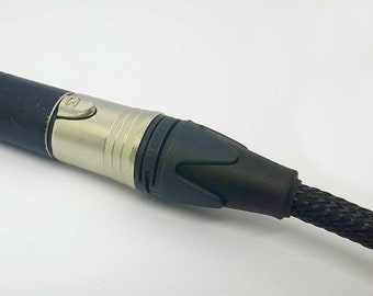 May include: Close-up of an XLR connector with a black cable. The connector has a silver metal body and a black plastic end. The cable is black and braided.