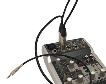 May include: A black audio cable with two 1/4 inch male connectors plugged into a Behringer Xenyx 502 USB audio mixer. The mixer has a variety of knobs and buttons for controlling audio levels and effects.