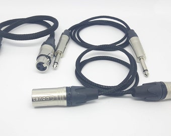 May include: Several black audio cables with silver connectors are arranged on a white surface. The cables have different connector types, including XLR and 1/4-inch jacks. The brand "tenon" is visible on one of the connectors.