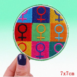May include: A colorful round patch with nine embroidered female symbols in different colors. The patch is 7 inches in diameter.