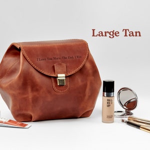 A large tan leather cosmetic bag on table with personaization on the front side. Near cosmetic items. Cosmetic bag for women with monogrammed. Best gift for her.
