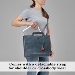 Puede incluir: Un bolso tote de cuero azul oscuro con una correa desmontable. El bolso tiene un asa superior y un peque&ntilde;o bolsillo en la parte delantera. Se puede ver un port&aacute;til dentro del bolso.