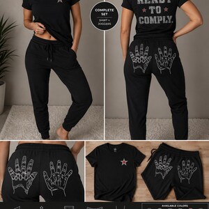 以下が含まれることがあります： 胸元に小さな赤い星があしらわれた黒のTシャツとジョガーパンツのセット。シャツの背面には赤い星と共に「READY TO COMPLY」の文字がプリントされている。パンツの背面には、2つの手の白い線画が描かれている。