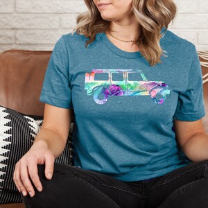 May include: A teal blue t-shirt with a colorful floral print of a jeep silhouette.