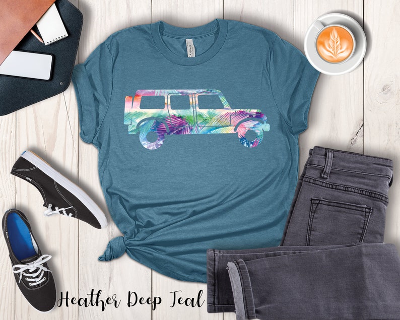 May include: A teal blue t-shirt with a floral print of a jeep silhouette. The text "Heather Deep Teal" is printed on the bottom of the shirt.