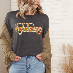 May include: A dark gray t-shirt with a floral print of a jeep. The jeep is outlined in black and the flowers are in shades of yellow, orange, and red.
