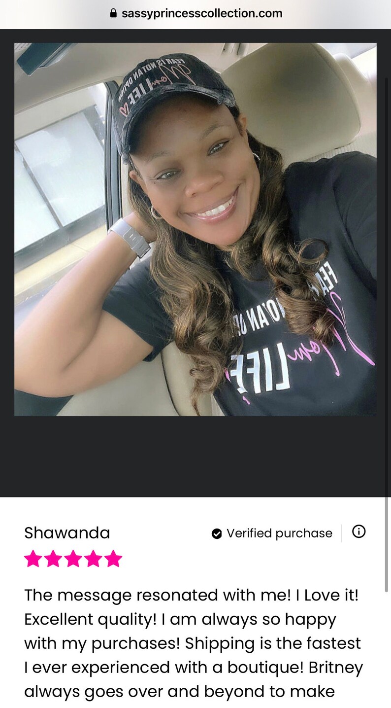 May include: A customer review with five stars for a black t-shirt with the text "My Life Is Not An Option" in pink lettering. The reviewer is wearing a black baseball cap with the text "Fear Is Not An Option" in pink lettering.