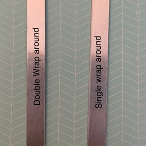 May include: Two silver metal strips with rounded edges. The strip on the left is labeled "Double Wrap around" and the strip on the right is labeled "Single wrap around".