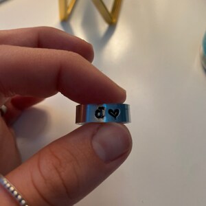 May include: A silver ring with a black heart and the letter "d" engraved on it.