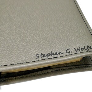 May include: Gray leather journal cover with black stitching and the name "Stephen G. Wolfe" embossed in black.