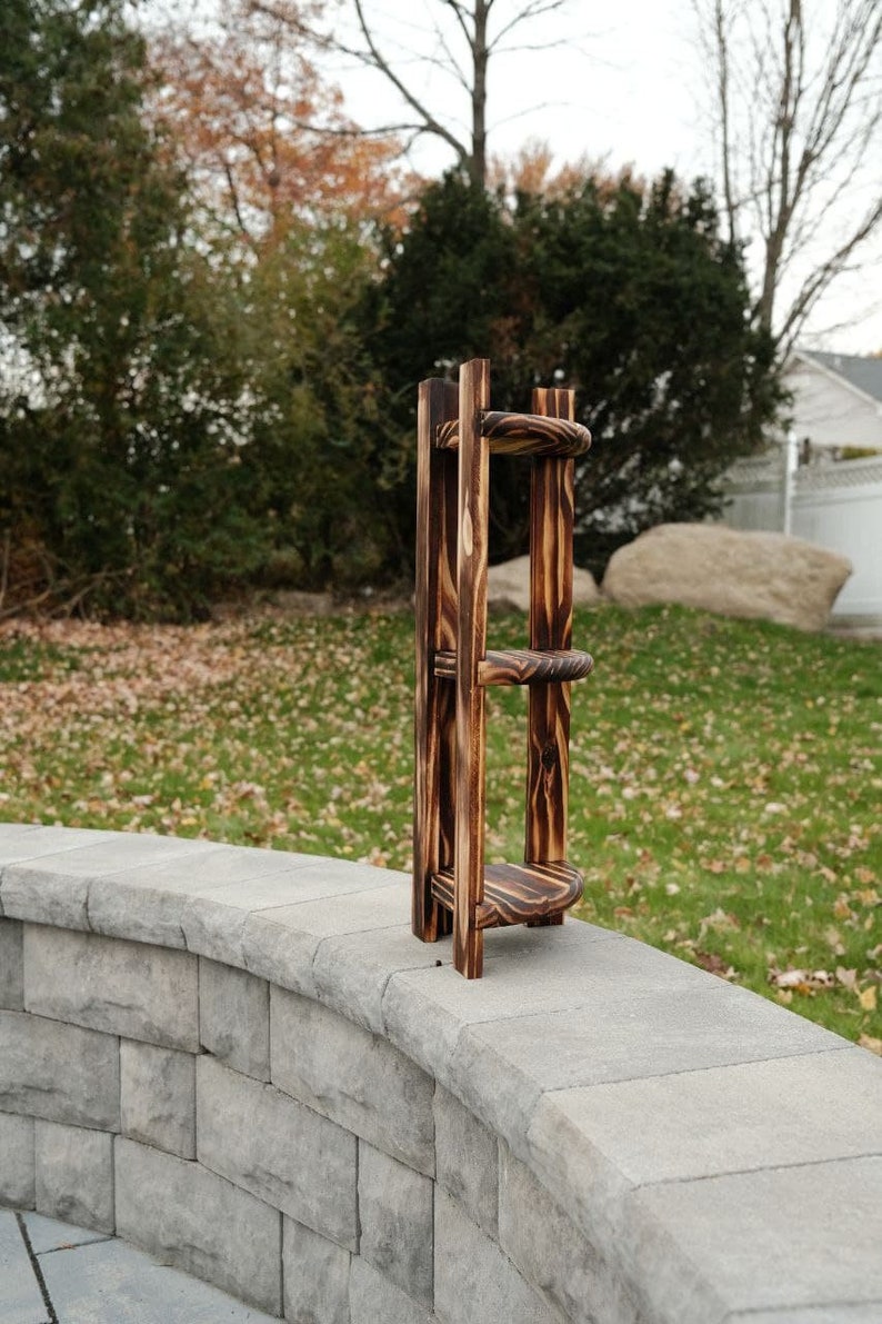 Puede incluir: Una estanter&iacute;a de madera de tres niveles con un acabado quemado. La estanter&iacute;a est&aacute; hecha de madera natural y tiene un aspecto r&uacute;stico. Est&aacute; sentada en una pared de piedra.