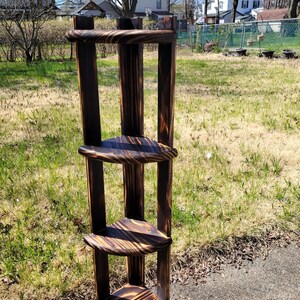 Puede incluir: Una estanter&iacute;a de esquina de madera marr&oacute;n oscuro con tres estantes. Los estantes est&aacute;n hechos de madera con un acabado r&uacute;stico. La estanter&iacute;a est&aacute; de pie sobre una superficie pavimentada.