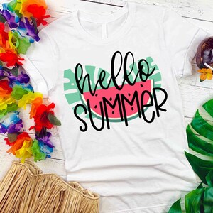 Puede incluir: Camiseta blanca con un gr&aacute;fico de sand&iacute;a verde y rosa y el texto "hello summer" en negro.
