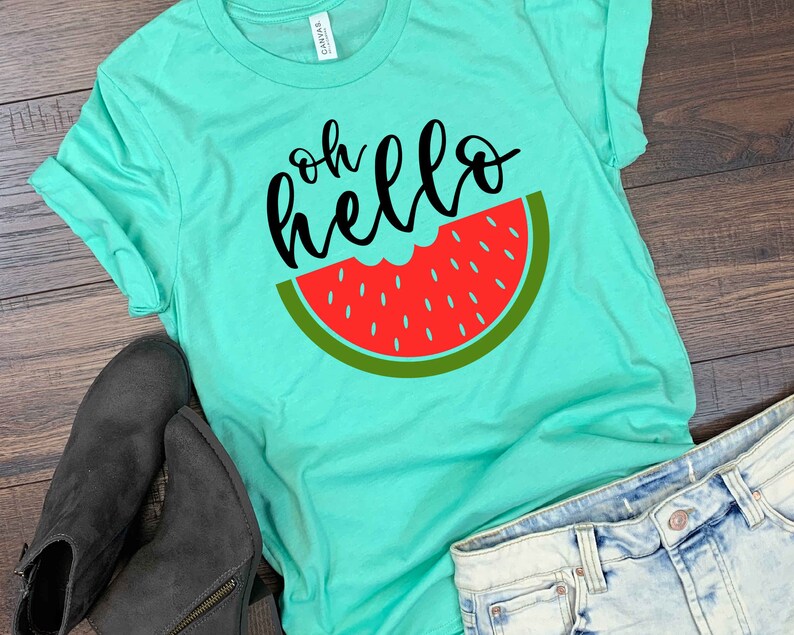 Puede incluir: Una camiseta turquesa con el texto "oh hello" en letra negra y un gr&aacute;fico de rodaja de sand&iacute;a roja.