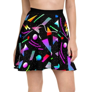 May include: A black skater skirt with a colorful geometric pattern. The pattern includes various shapes and colors, such as triangles, circles, and lines in shades of pink, blue, green, and yellow. The skirt is worn by a person with bare legs and black sneakers.