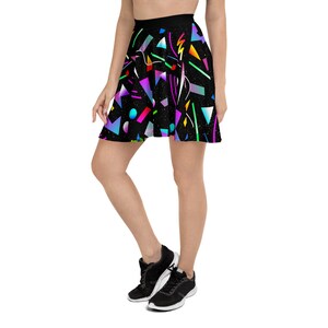 May include: A black skater skirt with a colorful geometric pattern. The pattern includes triangles, squares, circles, and lines in shades of pink, blue, green, yellow, and purple. The skirt has a black waistband and is made of a soft, stretchy fabric.