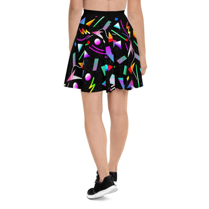May include: A black skater skirt with a colorful geometric pattern. The skirt features a variety of shapes and colors, including pink, blue, green, yellow, and orange. The skirt is made of a soft, comfortable fabric and is perfect for a casual or dressy occasion.