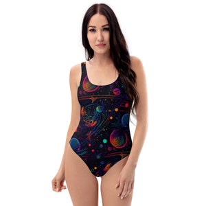 May include: A black one-piece swimsuit with a colorful galaxy print featuring planets, stars, and comets. The swimsuit has a scoop neck and a low back.