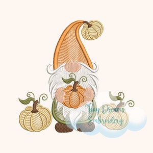 May include: Embroidered design of a gnome holding a pumpkin with two additional pumpkins on either side. The gnome is wearing a brown hat and has a white beard. The pumpkins are orange and white.