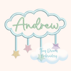 May include: A light blue cloud-shaped embroidery design with the name "Andrew" in green script. Below the cloud hang three stars in pastel colors. The design also includes the text "Tiny Dreams Embroidery".