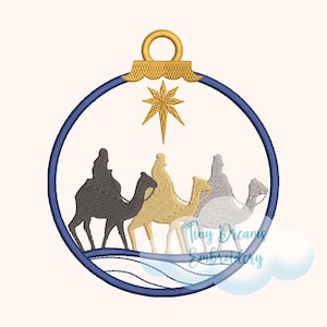 May include: A blue and gold Christmas ornament with a star and three wise men riding camels. The ornament is in the shape of a circle with a gold hanger.