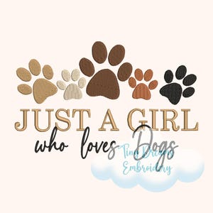 Peut inclure: Broderie représentant une ligne d'empreintes de pattes en marron, beige et noir avec le texte "Just a girl who loves dogs" en lettres dorées.