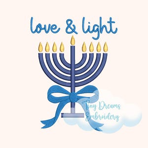 May include: A blue embroidered menorah with eight gold flames and a central flame, with a blue bow at the base. The words "love & light" are written above the menorah in blue script. The image has a light beige background.