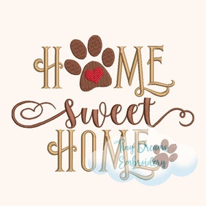 Op de afbeelding: Borduurwerk "Home sweet home" met een bruine pootafdruk met een rood hart in het midden. De tekst is in goud.