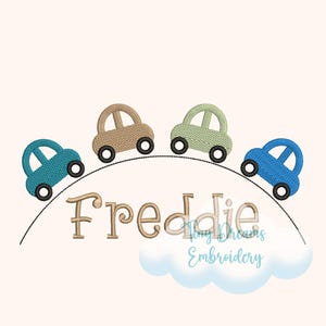 Puede incluir: Un diseño bordado con cuatro coches de juguete en verde azulado, beige, verde y azul, rodando por una línea curva. El nombre "Freddie" está escrito en cursiva debajo de los coches, con una nube y el texto "Tiny Dreams Embroidery".
