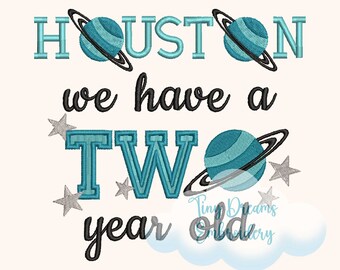 May include: Embroidered design with the text "Houston we have a two year old" with planets and stars. The text is in black and the planets and stars are in blue and gray.
