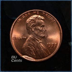 May include: A copper-colored 1977 Lincoln penny. The obverse features a profile of Abraham Lincoln, the word "LIBERTY", and the phrase "IN GOD WE TRUST". The year "1977" is visible. The text "BU Cents" is also present.