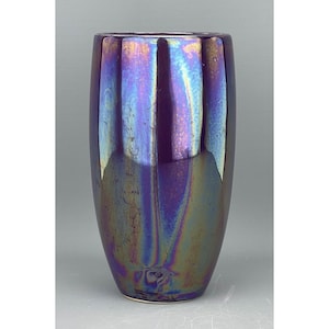 May include: A tall, iridescent purple vase with a rounded bottom and a slightly flared opening. The vase has a metallic sheen and a textured surface.