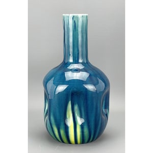 Puede incluir: Un jarrón de cerámica azul y verde con cuerpo redondeado y cuello estrecho. El jarrón tiene un acabado brillante y un patrón a rayas.